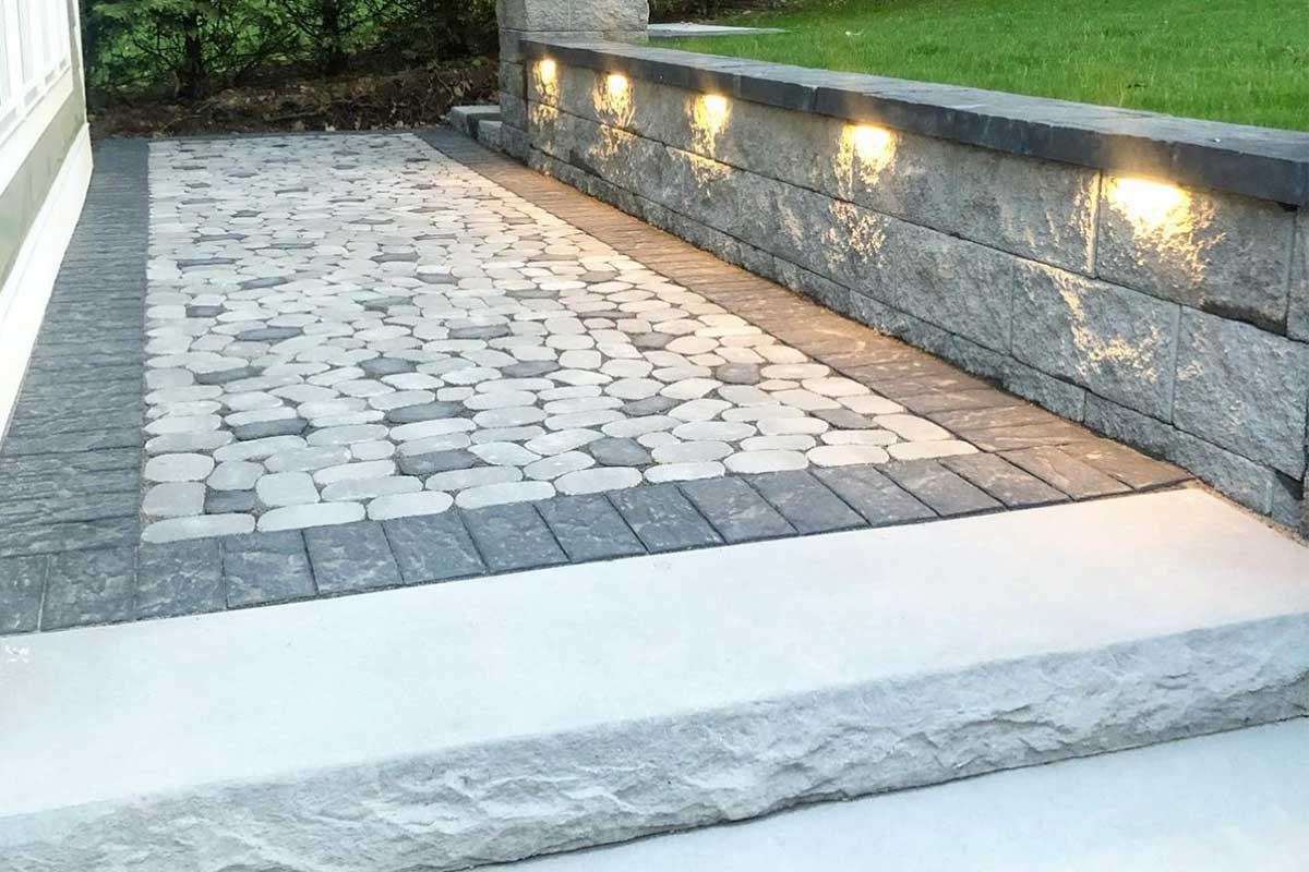 The wall is built into the slope. Part of it is below the ground, not just sitting on top.

It’s angled slightly backward to lean into the slope, which gives it strength against the weight of the soil.

A drainage system is often installed behind the wall to make sure water doesn’t build up and create pressure.

Materials like concrete blocks, stone, or treated timber are chosen based on the height of the wall and the soil type.
