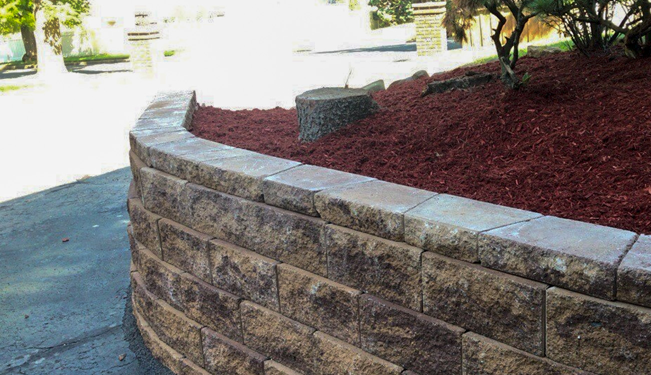 Curved stone retaining wall with mulch.