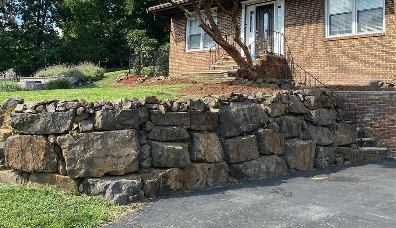 Sturdy stone retaining wall by house.