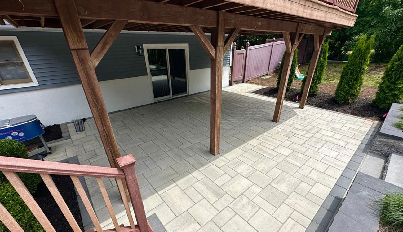 Paver patio under wooden deck structure.