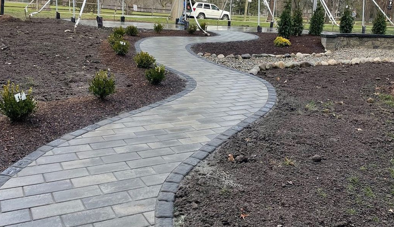 Curved paver walkway through landscaped area.